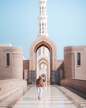 Person walking in front of a grand mosque showcasing beautiful modern Islamic architectural design.