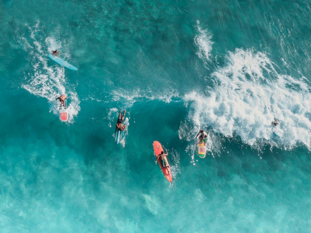 Exciting aerial shot of surfers tackling vibrant ocean waves, perfect for capturing the thrill of water sports.