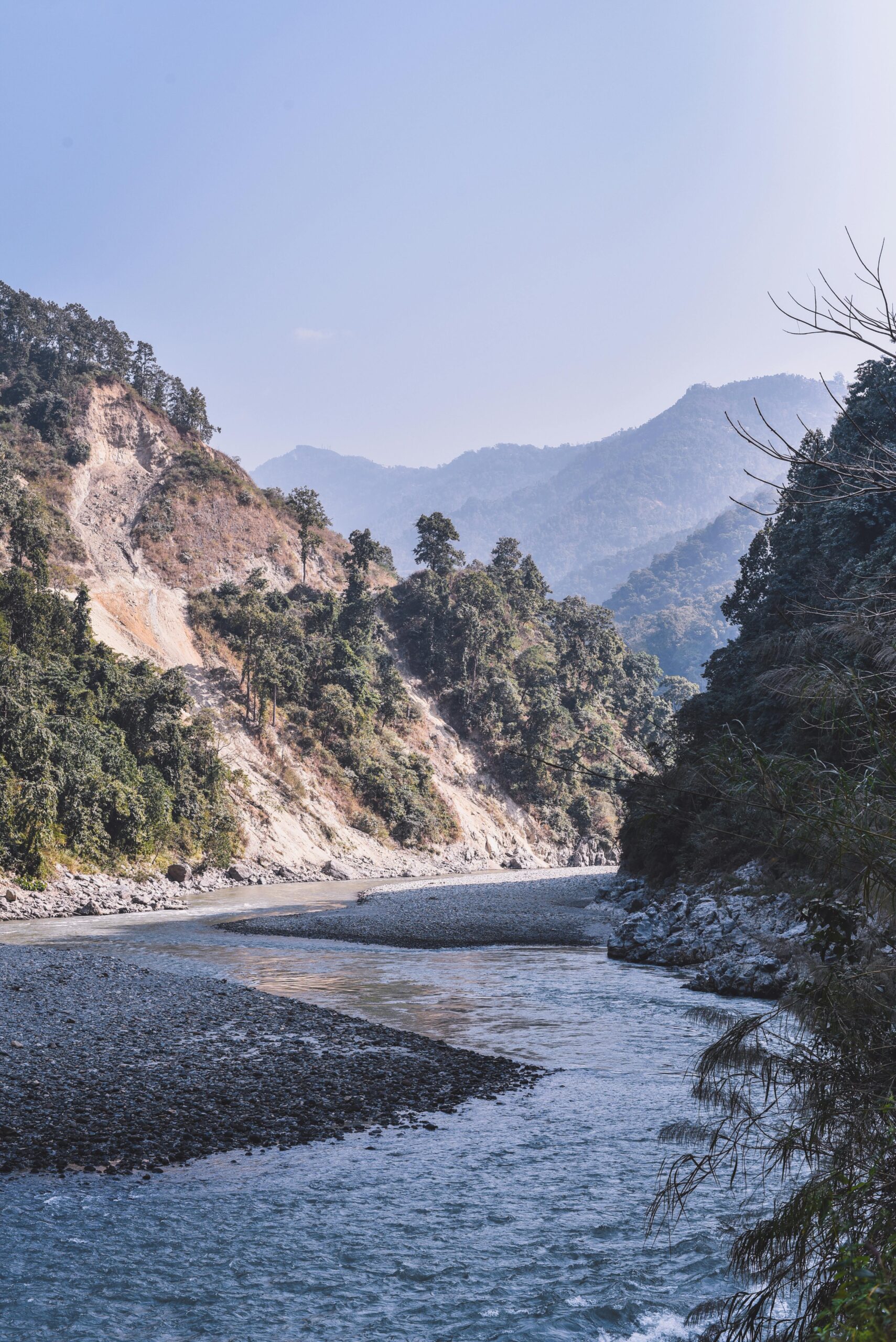 Captivating view of a tranquil river winding through lush Himalayan mountains in Sikkim, India.
